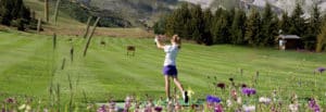 Golf Club de Courchevel | ©Olivier BARJON, junior joue au golf avec fleurs en premier plan