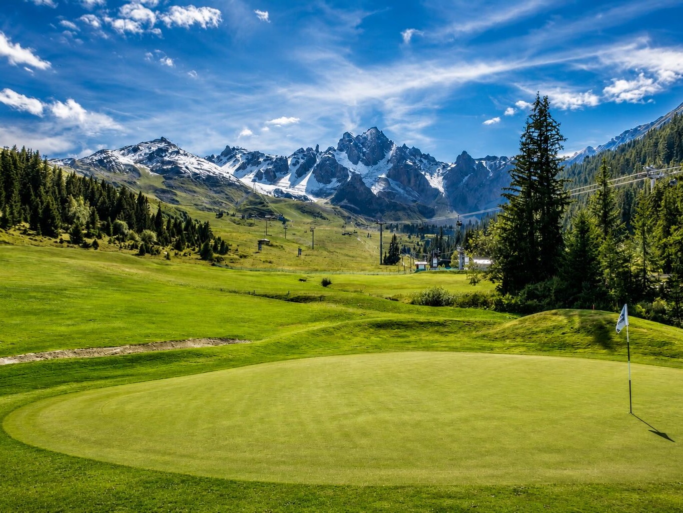 Green du Golf Club de Courchevel en montagne avec vue sur les sommets alpins enneigés.
