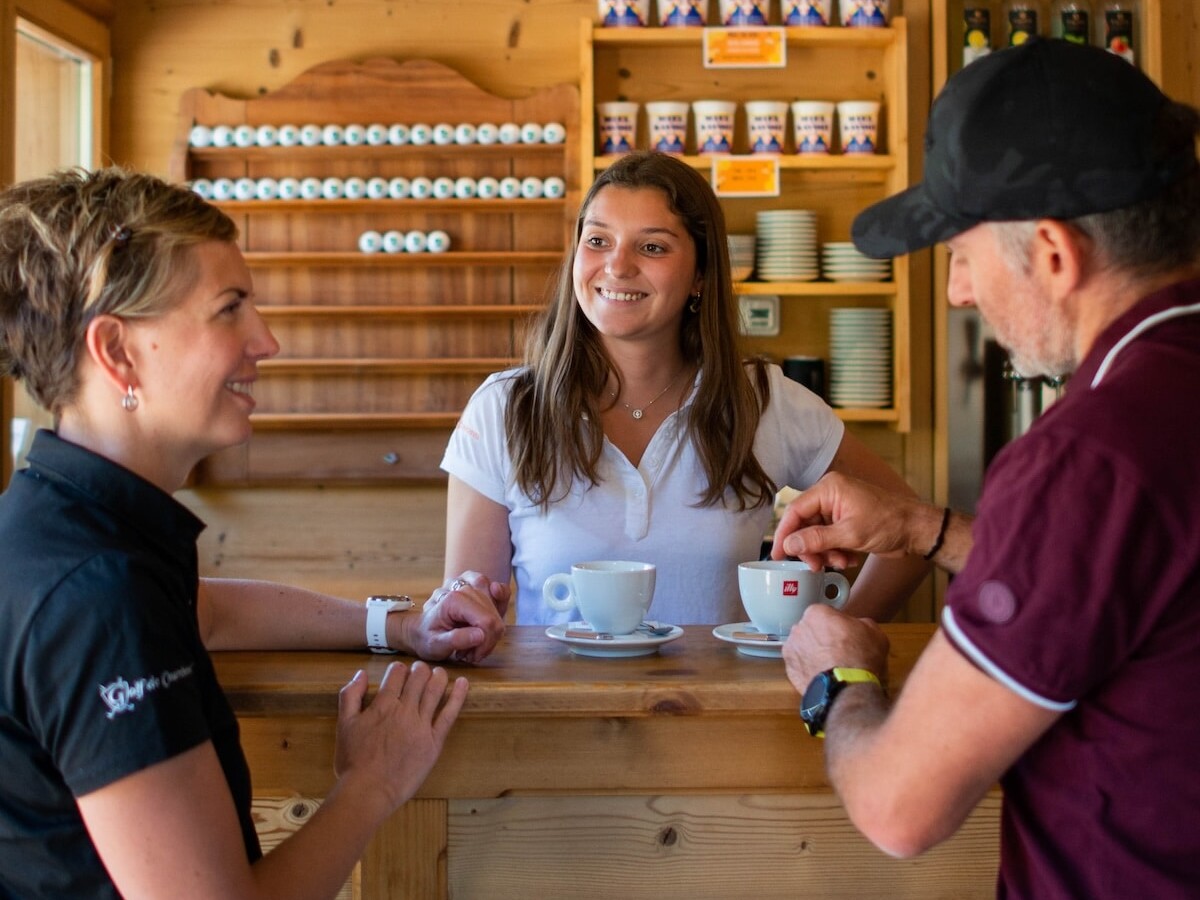 Couple accueilli au Club House du Golf Club de Courchevel par une hôtesse autour d'un café.