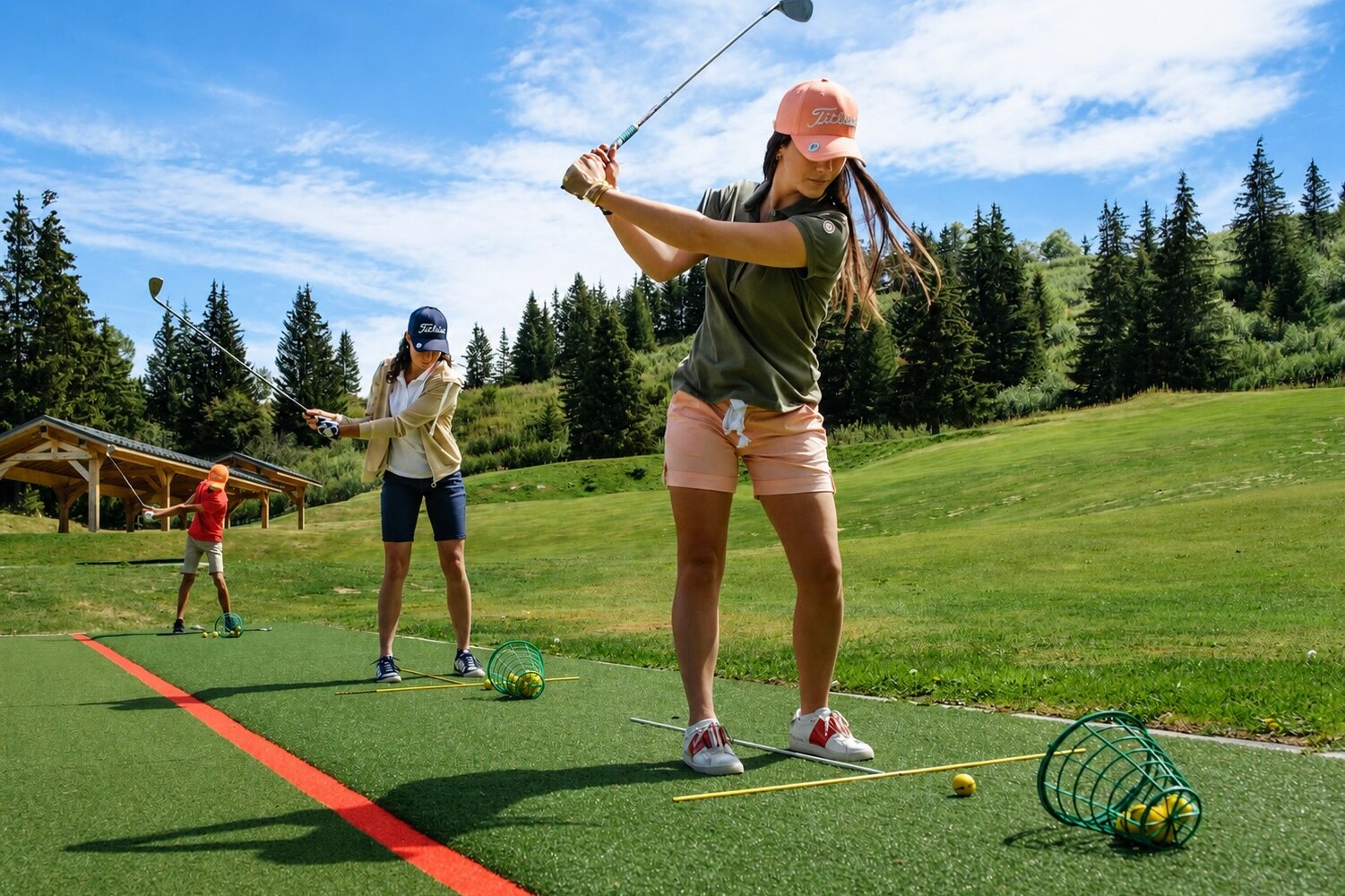 Female golfers practising at the Courchevel Golf Club practice area with the Alps as a backdrop.