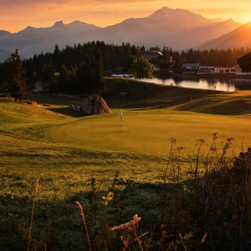 Green du Golf Club de Courchevel au coucher du soleil avec vue sur les montagnes des Alpes.